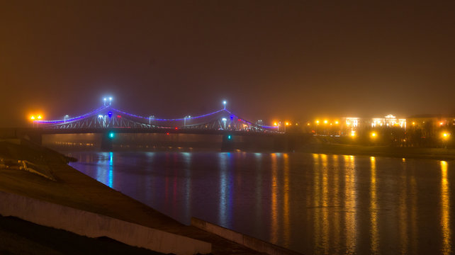 Starovolzhsky bridge in fog and night lighting. The bridge over the Volga River in Tver. Built in 1897-1900.