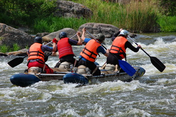 Team of  athletes on an inflatable catamaran row up the stream in a thresholds. Southern Bug river,...