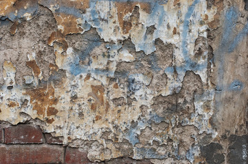Fragment of the destroyed wall with cracked stucco and clay brick.