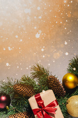 New Year's gift, toy, card, cones. New Year composition on gray concrete background. Snowflakes in the foreground. Warm light in the corner.