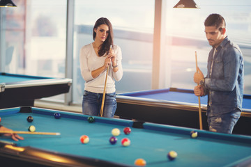 Fototapeta premium Group of young friends playing billiard