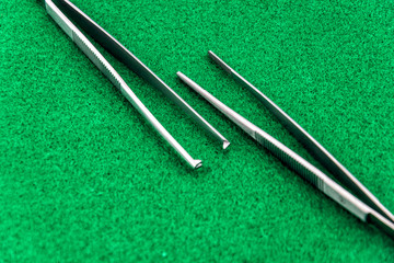 Two types of surgical tweezers isolated on green background