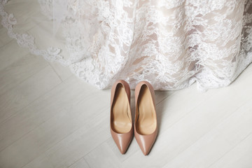 Wedding shoes cream-coloured white on the floor. Wedding dress.