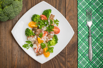 Roasted meat, white rice and vegetables. Wooden background. Top view. Close-up