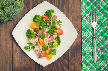 Roasted meat, white rice and vegetables. Wooden background. Top view. Close-up