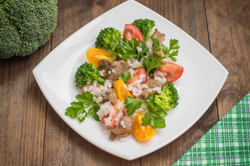 Roasted meat, white rice and vegetables. Wooden background. Top view. Close-up