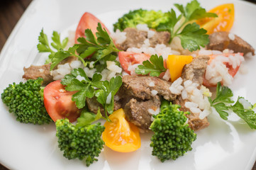 Roasted meat, white rice and vegetables. Wooden background. Top view. Close-up