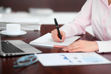 Closeup of a business woman writing in a notebook