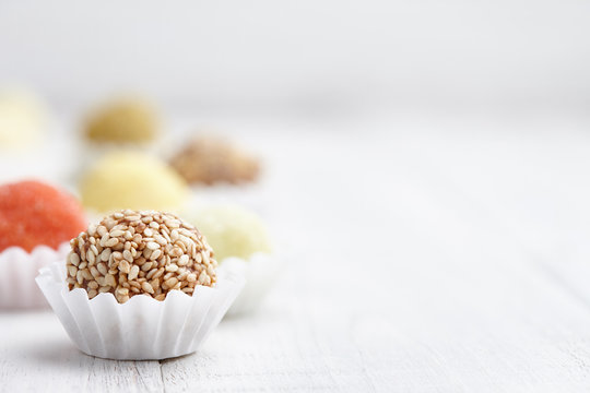 Chocolate truffle candies with sesame seeds on white wooden background