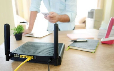 closeup of a wireless router and a man using smartphone on livin