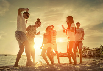 Friends funny dance on the beach under sunset sunlight.
