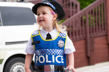 Baby caucasian girl toddler dressing up playing in police unifor