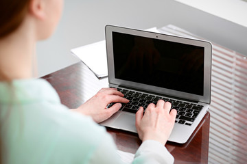 Fototapeta premium Business woman hands in a green blouse sitting at the desk in the office and typing on the laptop .