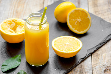 Fototapeta na wymiar freshly squeezed orange juice in glass bottle on wooden background