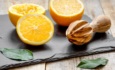 cut oranges in half and juicer on wooden background