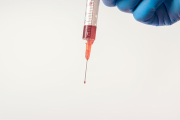 Hand in glove with syringe on white background.