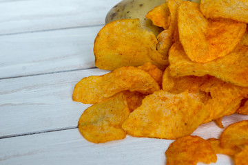 Fresh raw potatoes and chips with spice on a white wooden background
