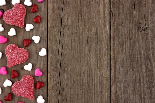 Valentines Day heart shaped candy side border on a rustic wood background