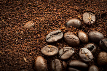 Closeup of mixed heap of roasted coffee beans and ground coffee with copy space