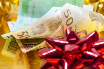 Money with red gift bow on golden background