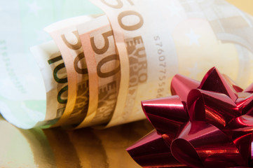 Money with red gift bow on golden background

