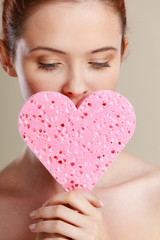 woman holding pink heart sponge in hands.