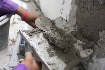 Closeup hands of the workers were plastering the walls with trowel. In construction site.
