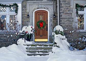 white front door with Christmas wreath on a snowy day