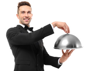 Handsome waiter holding metal tray with cover on white background