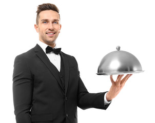 Handsome waiter holding metal tray with cover on white background