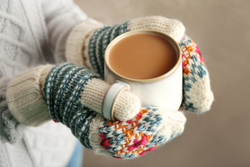 Female hands in mittens holding a cup of coffee, closeup