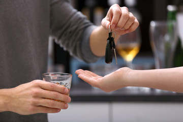 Close up view of drunk man giving car key to woman, on blurred background. Don't drink and drive concept