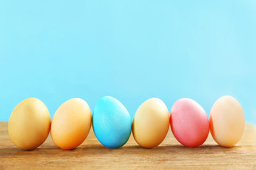 Colorful Easter eggs on wooden table against blue background