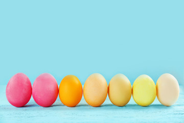 Easter eggs on wooden table against color background