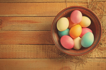 Bowl with colorful Easter eggs on wooden table