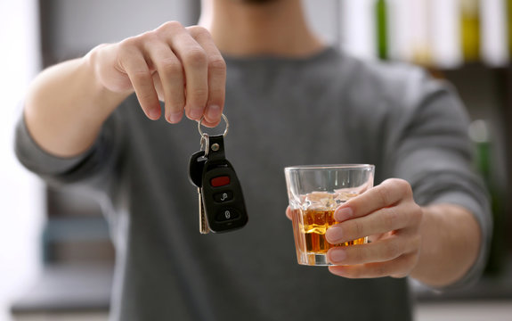 Close up view of man with car key and alcoholic beverage. Don't drink and drive concept