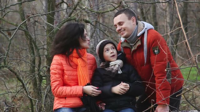 Young family sitting on a log in the woods.