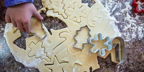 Child pressing a snowman cookie cutter into sugar cookie dough