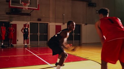 Two basketball players playing one on one while their teammates stand behind the lines - Powered by Adobe