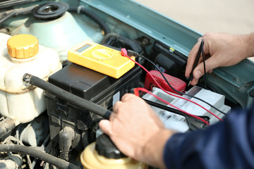 Mechanic hands with scan tool diagnosing car in open hood. Closeup