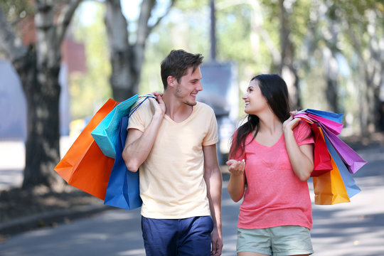 Happy couple carrying colorful bags outdoors