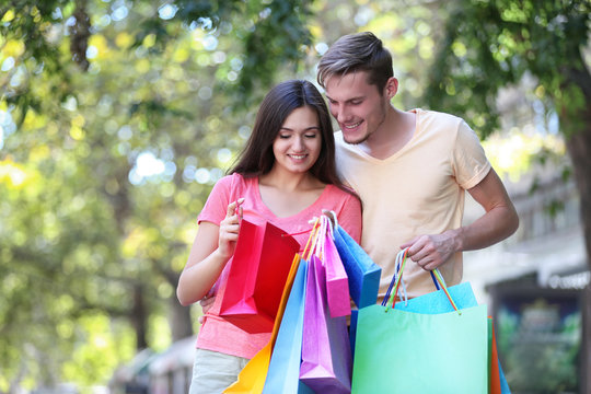 Happy couple with colorful shopping bags in park
