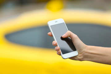 Woman ordering taxi by cellphone on blurred car background