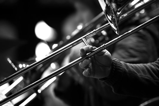 Hand of man playing the trombone in black and white