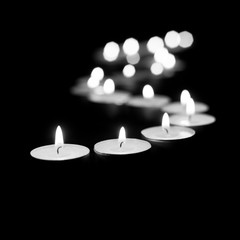 Obraz na płótnie Canvas Burning candles on a black background in black and white