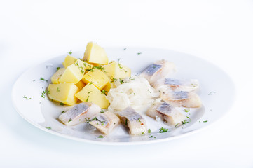 Herring with boiled potatoes, onions and herbs on a white background