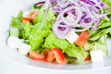 Vegetable salad with tomatoes, cucumbers, feta cheese, onions and tomatoes on a white background