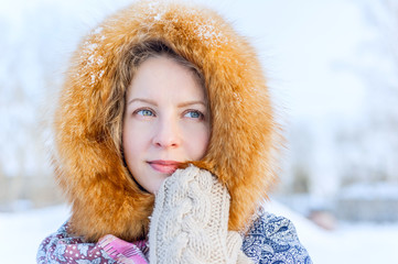 beautiful young woman in a fur hood winter. Outdoor portrait. Russian shawl and mittens