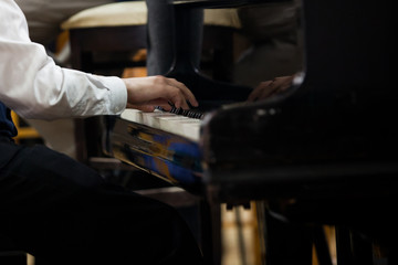 Hands of a child playing the piano closeup in dark colors