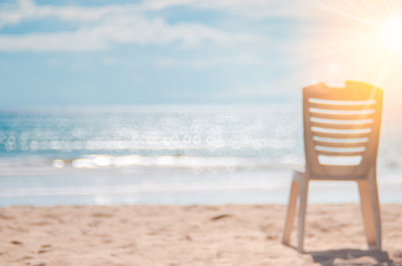Blur old broken chair on tropical beach with bokeh sun light wave abstract background.